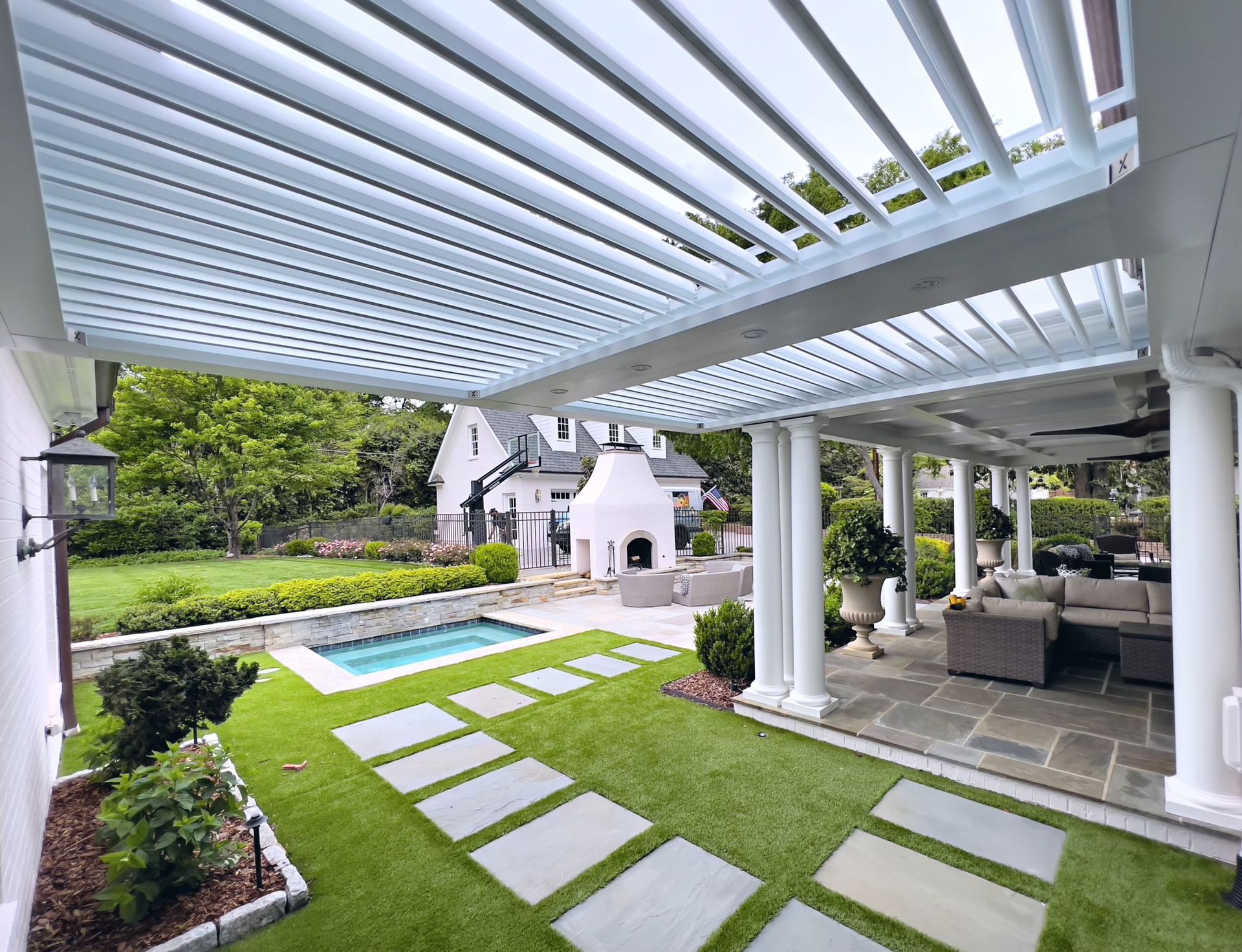 A patio with a pergola and a pool in the backyard.