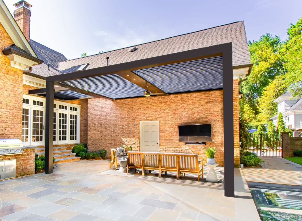 a patio with a table and chairs under a pergola in front of a brick house .