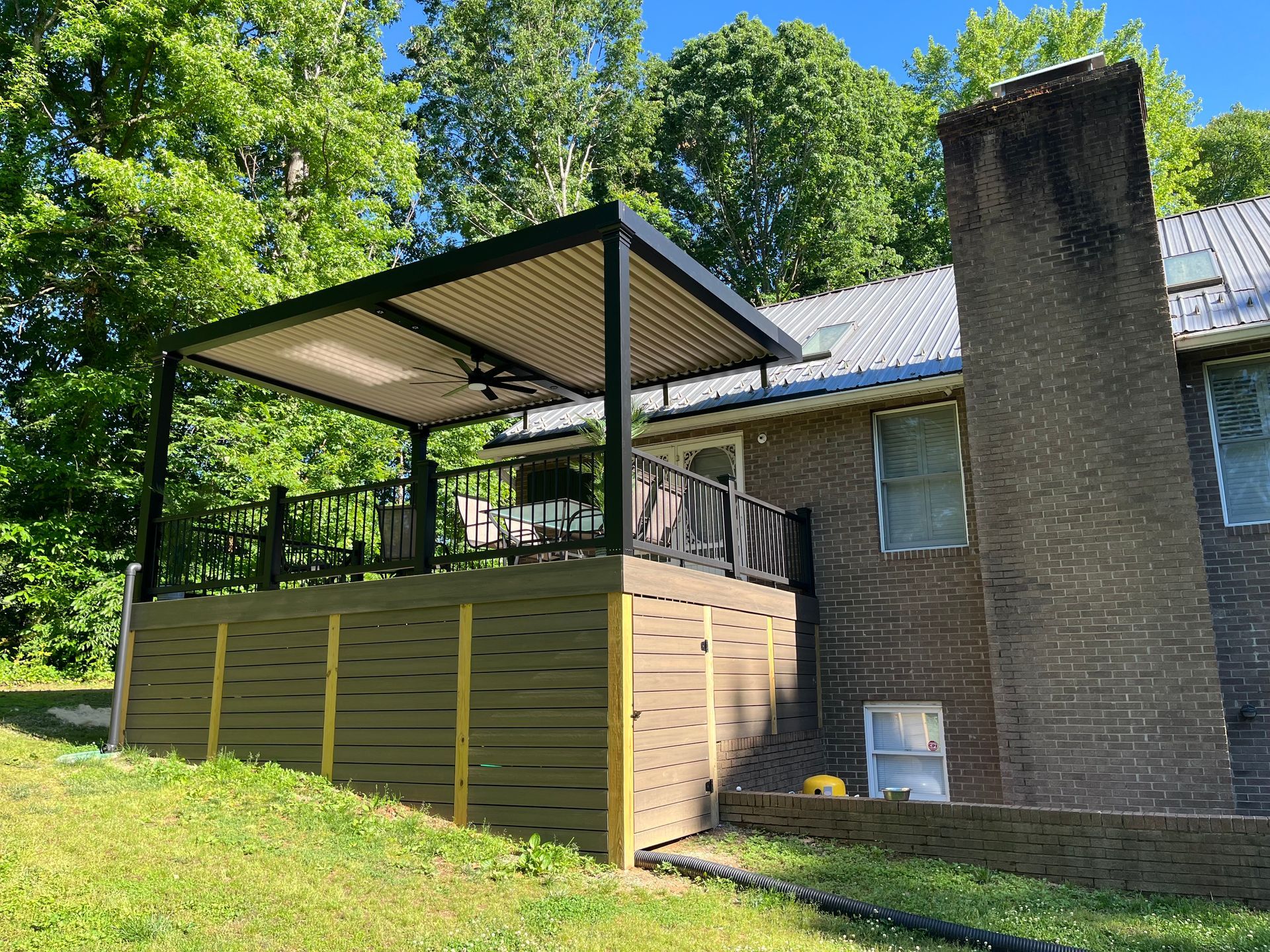 A brick house with a wooden deck and a canopy over it.
