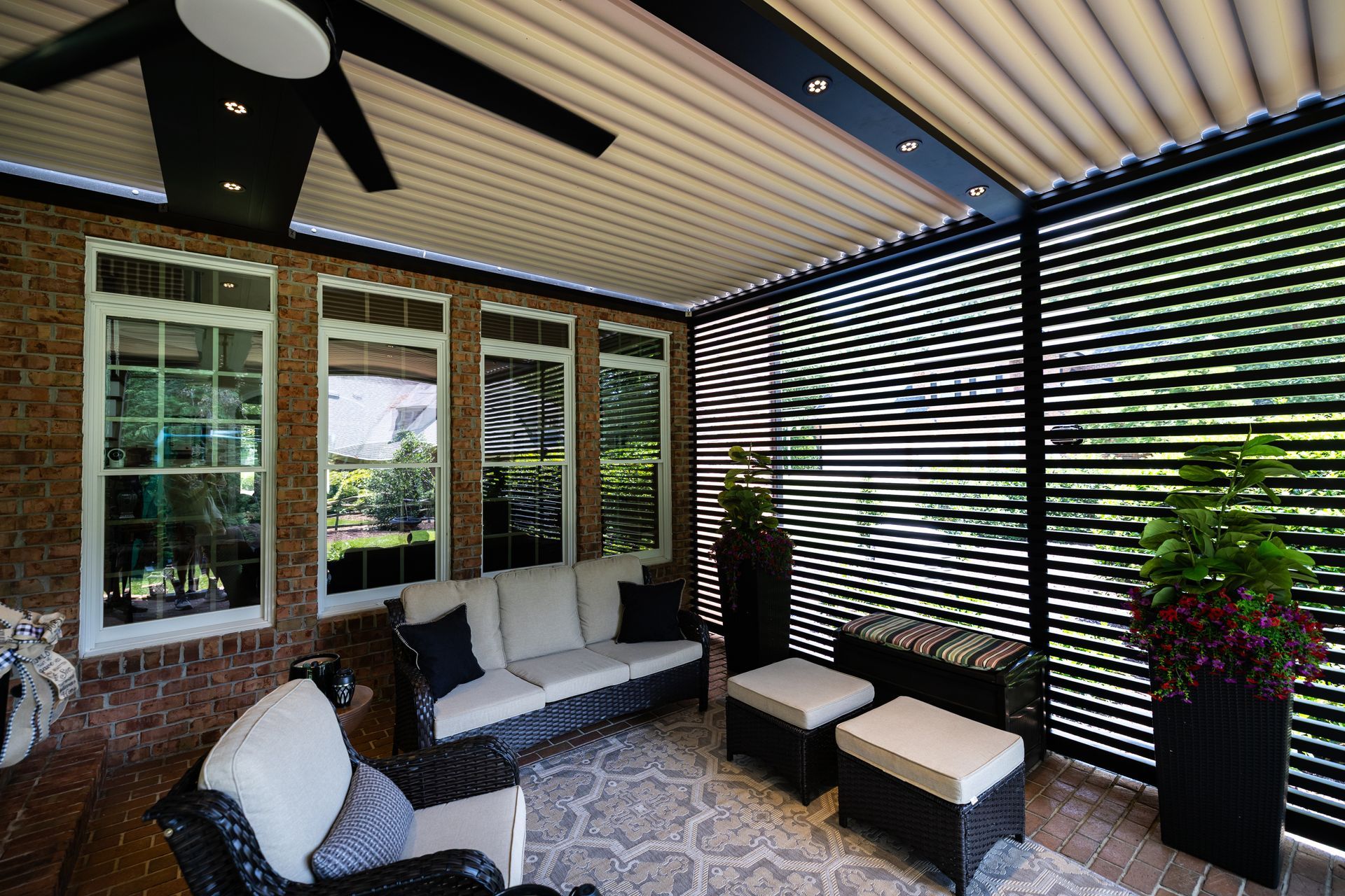 A living room with a couch , chairs , ottomans and a ceiling fan.
