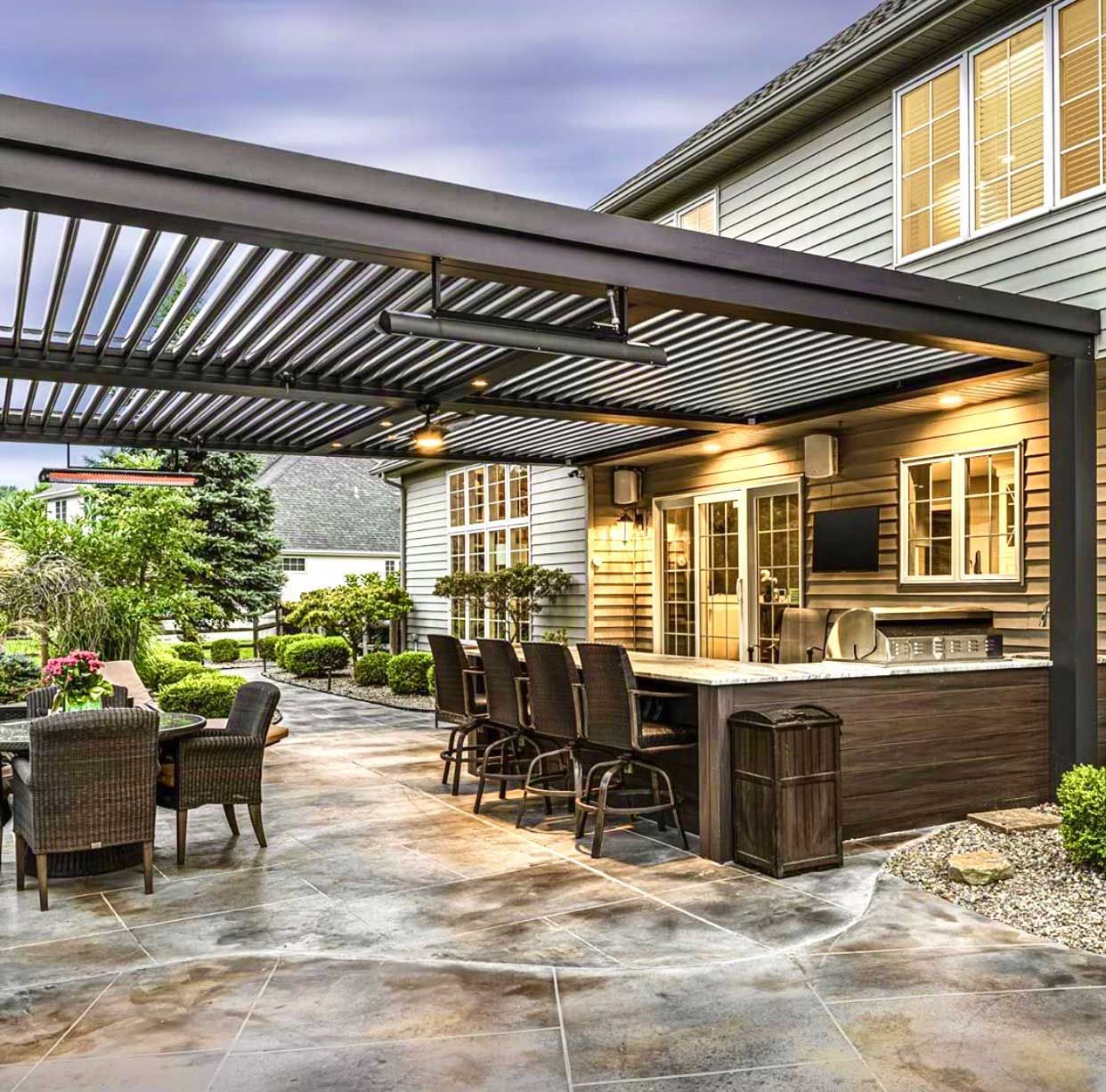 A patio with a pergola, tables and chairs, and a kitchen