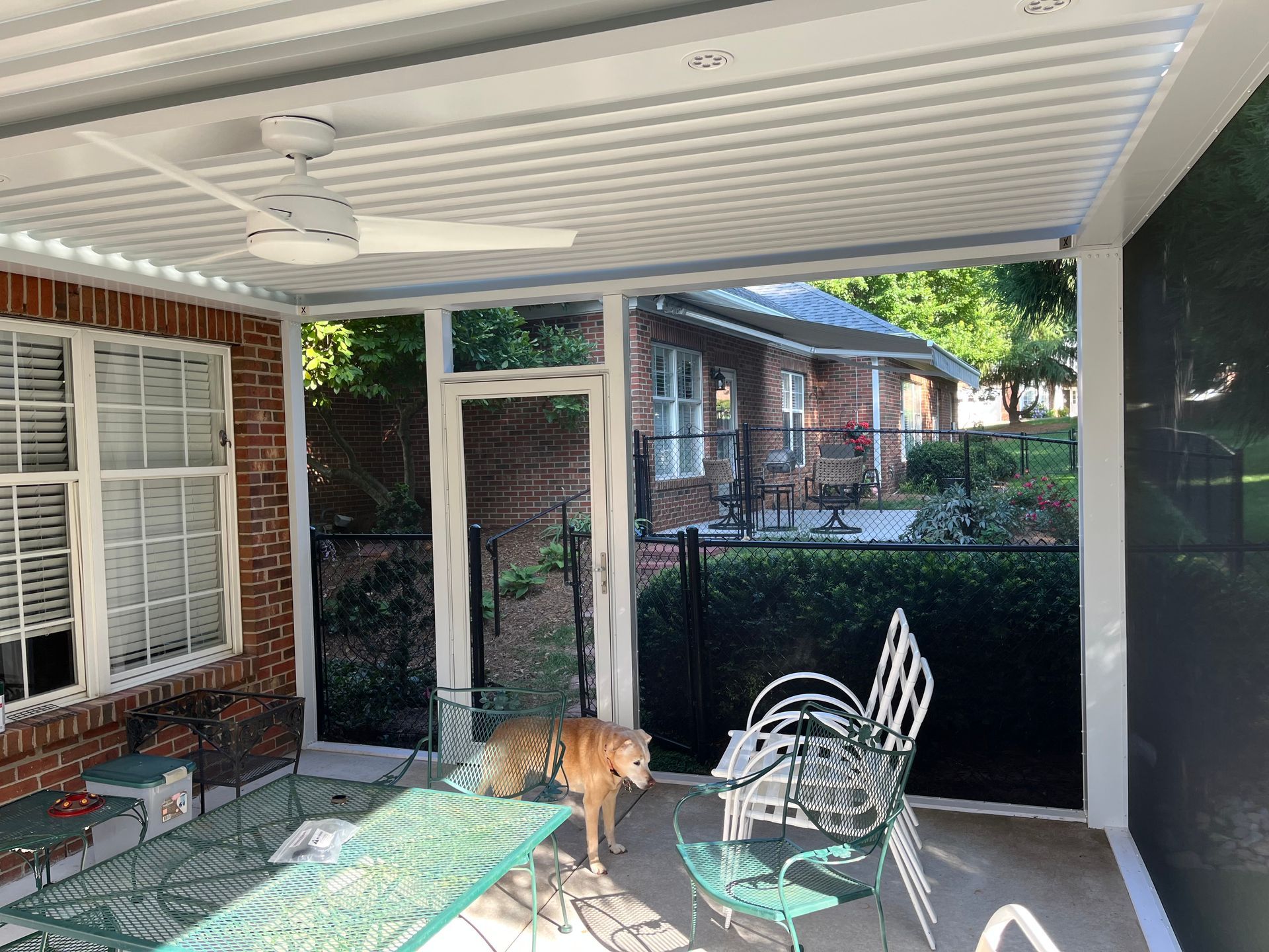 A dog is standing on a porch next to a table and chairs.
