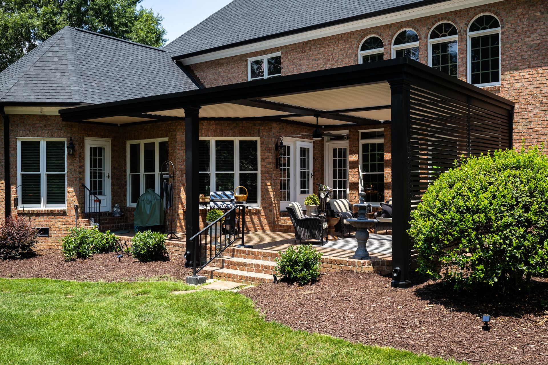 A large brick house with a pergola on the back patio.