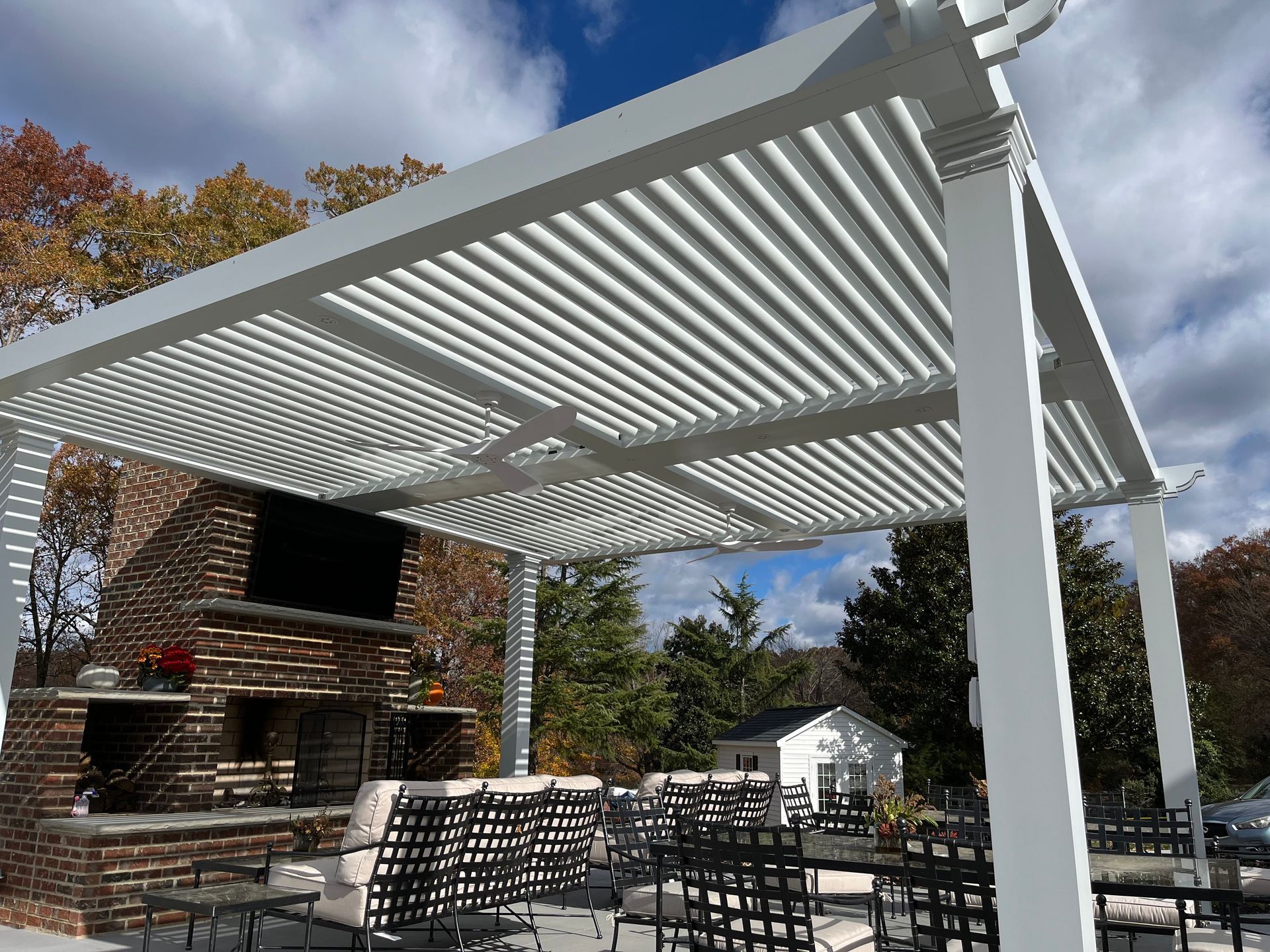 A white pergola is sitting in front of a brick fireplace.