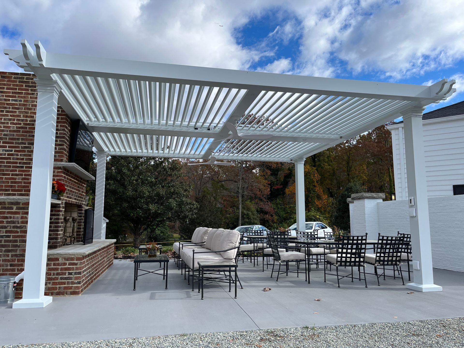 A white pergola with a couch and chairs underneath it.