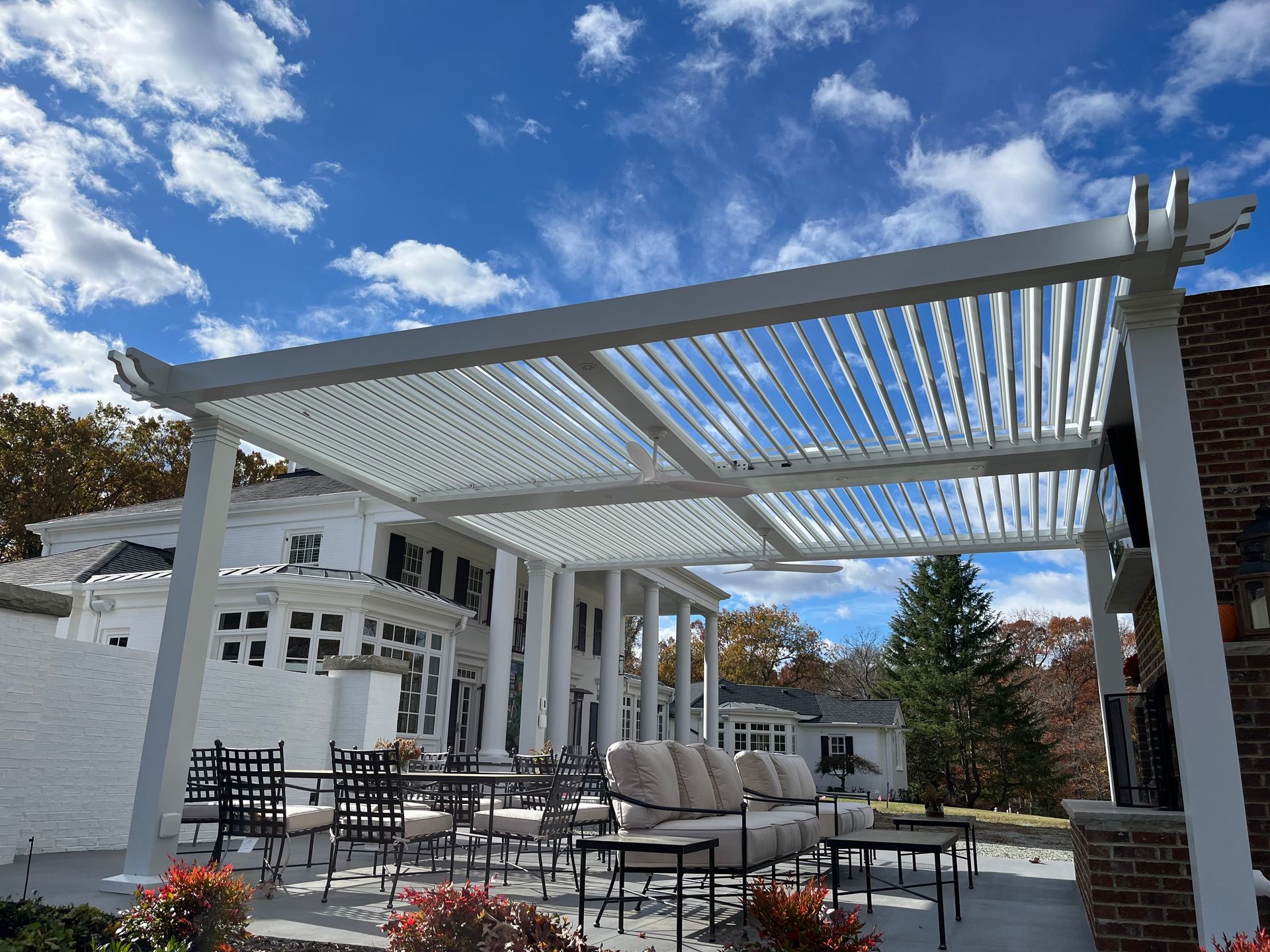 A white pergola is sitting on top of a patio next to a house.