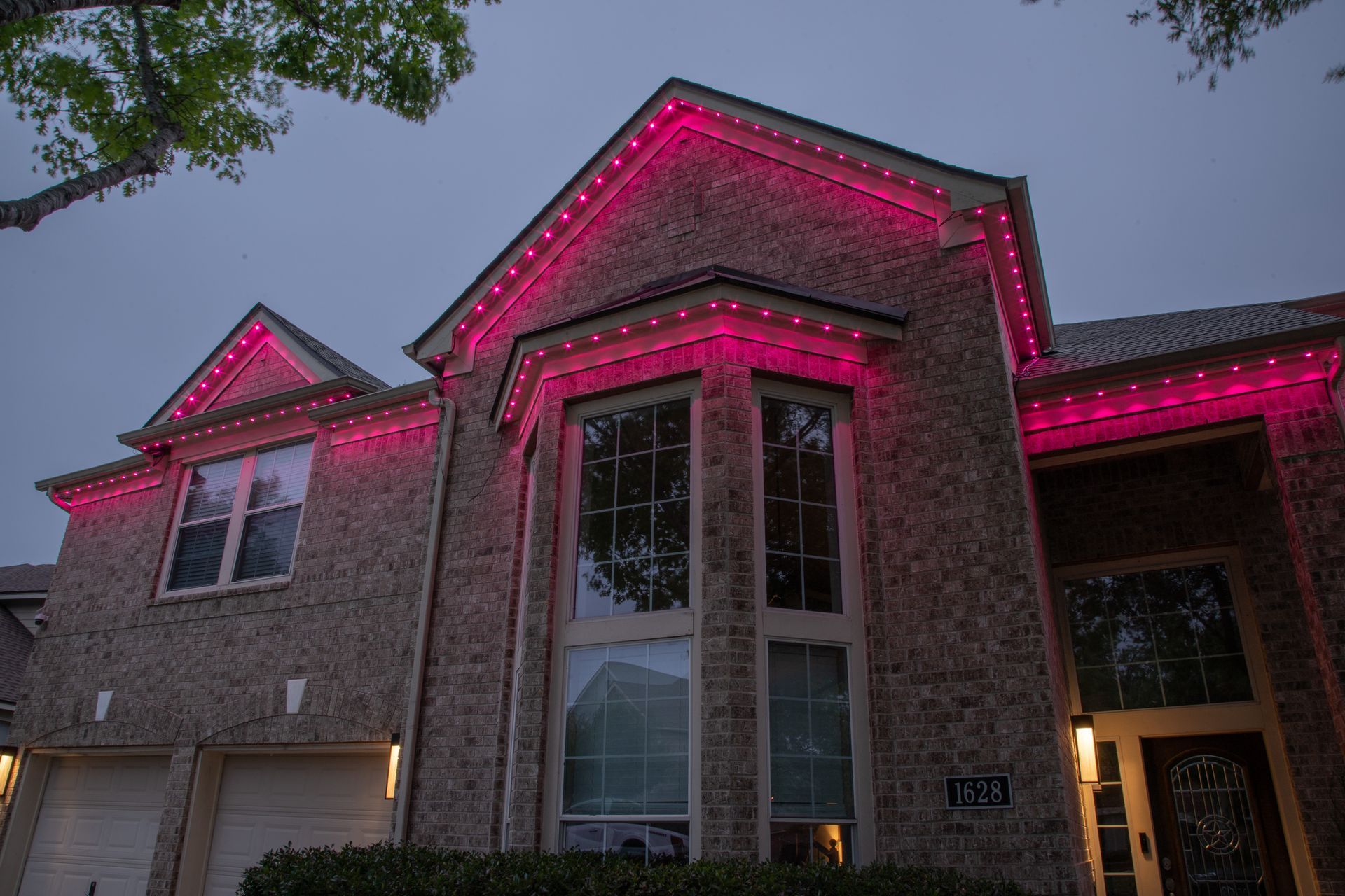 A large brick house with pink lights on it at night.