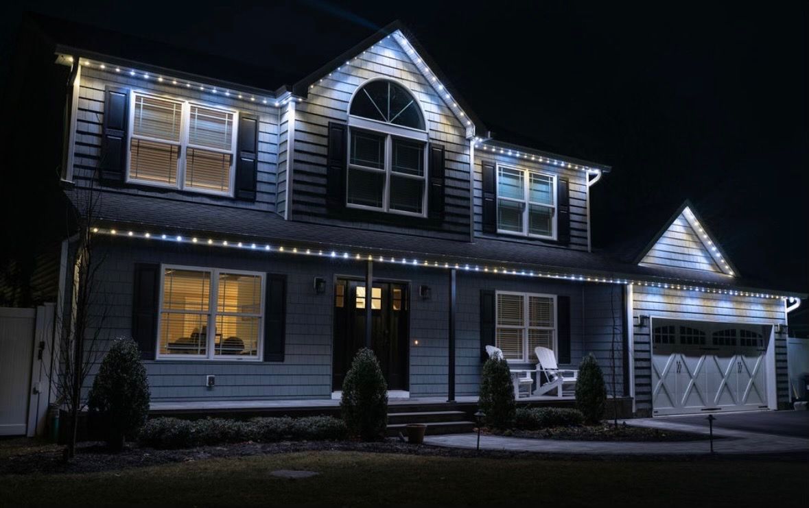 A large house with Christmas lights on it is lit up at night.