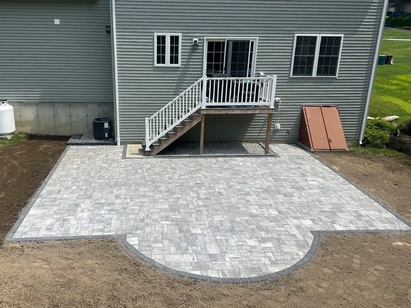 A patio with a deck and stairs in front of a house.