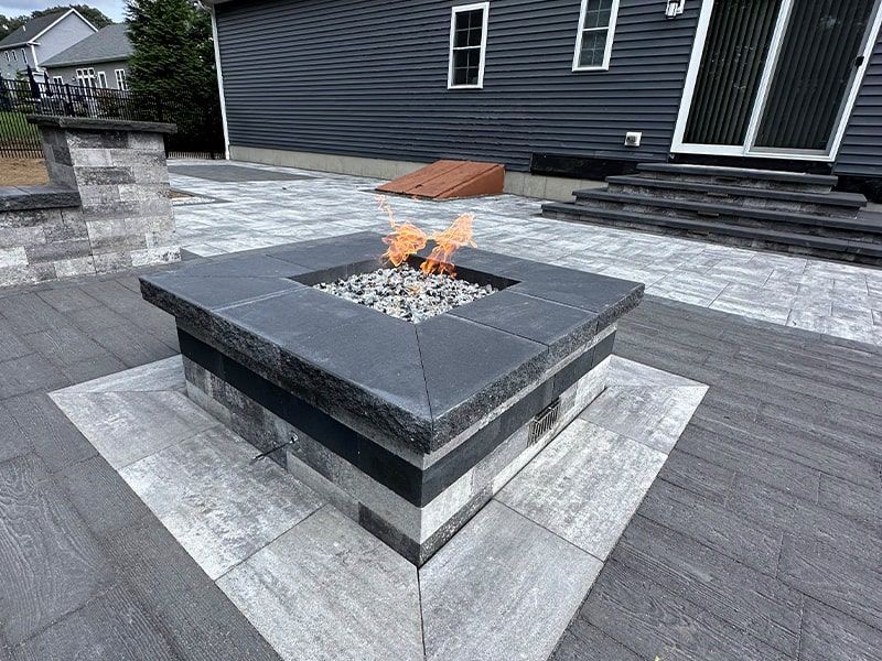 A fire pit is sitting on a patio in front of a house.