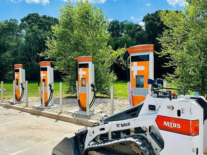 A bulldozer is parked in front of a row of charging stations.