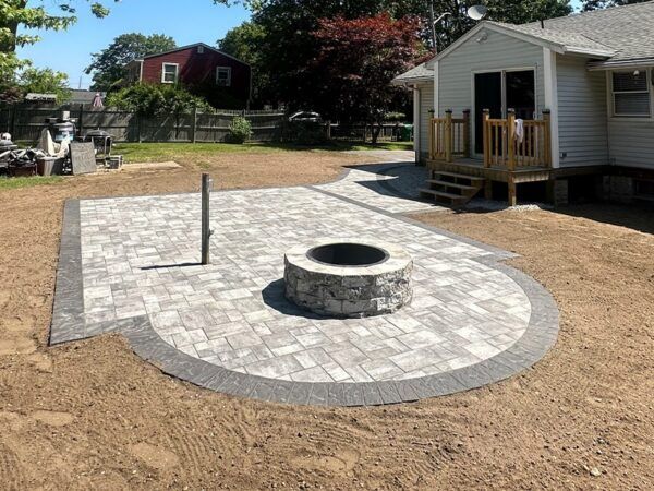 A fire pit in the middle of a patio in front of a house.