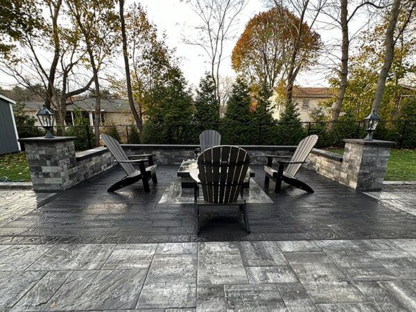 A patio with chairs and a table with trees in the background