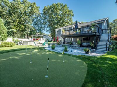 There is a putting green in the backyard of a house.