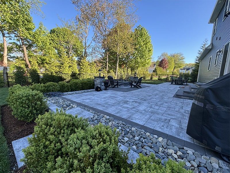 A large patio with a table and chairs in the backyard of a house.