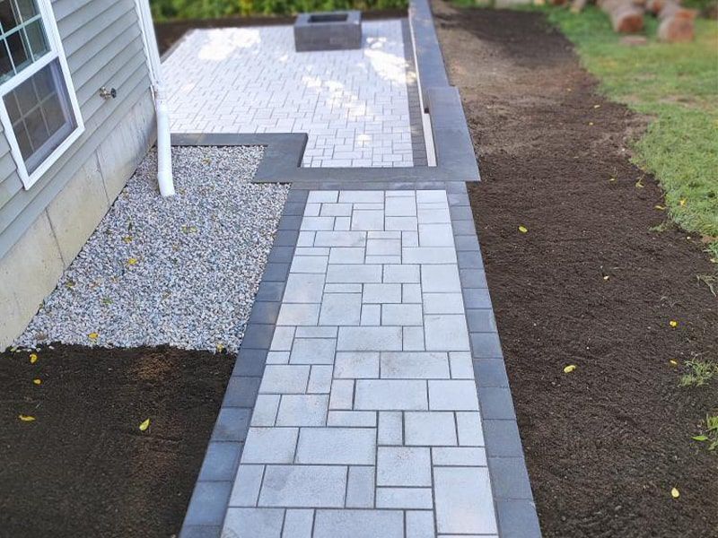 A walkway leading to a patio with a fire pit
