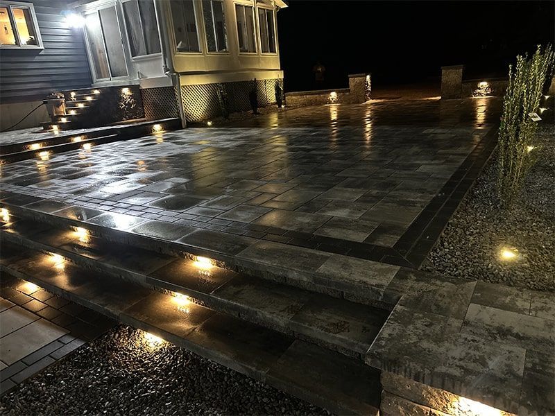 A patio with stairs and lights on it at night.