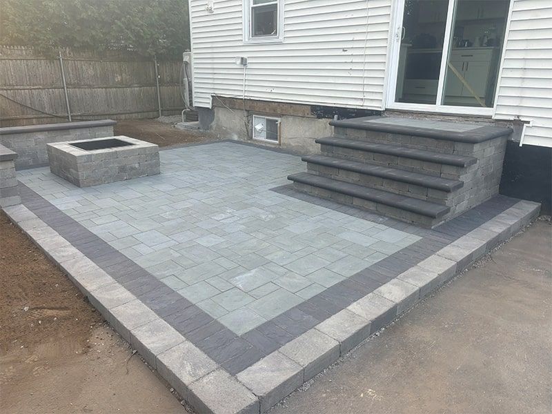 A patio with stairs and a fire pit in front of a house.