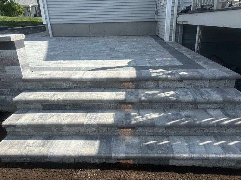 A set of stairs leading up to a patio in front of a house.