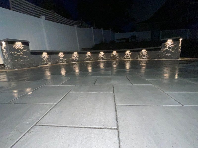 A tiled floor with a fence in the background at night.