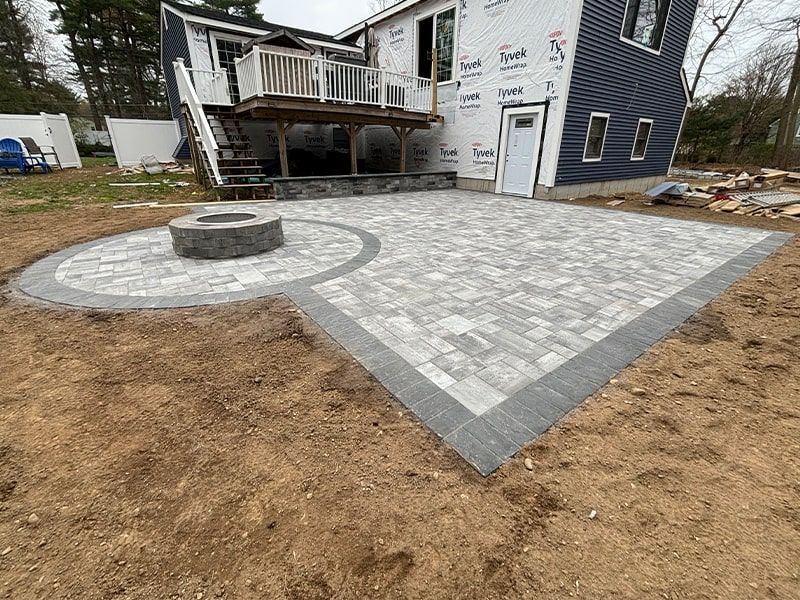 A patio with a fire pit in the middle of it in front of a house.