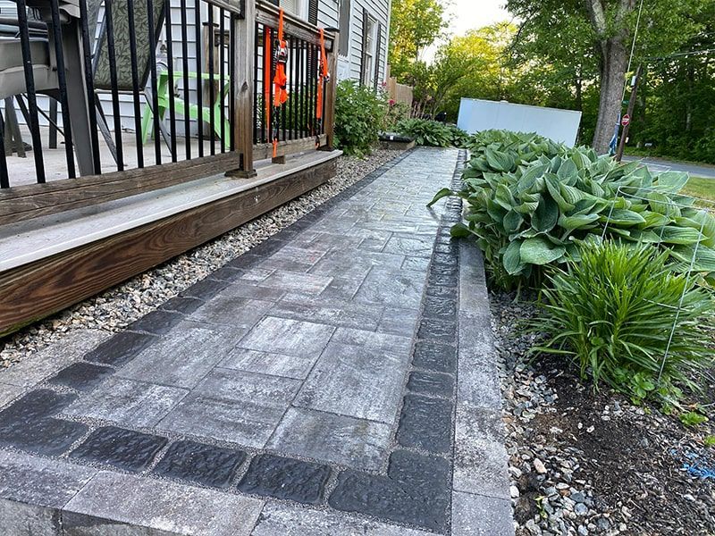 A brick walkway leading to a deck and a house.