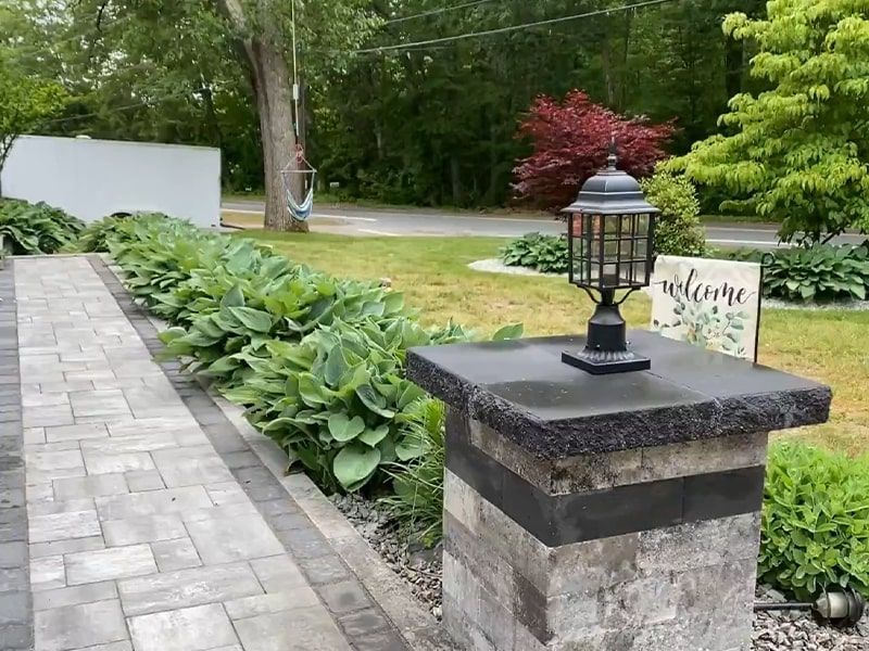 A stone pillar with a lamp on top of it in a garden.
