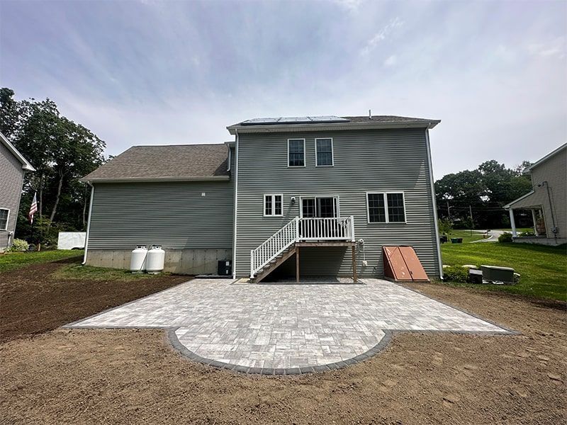 The back of a house with a patio in front of it.
