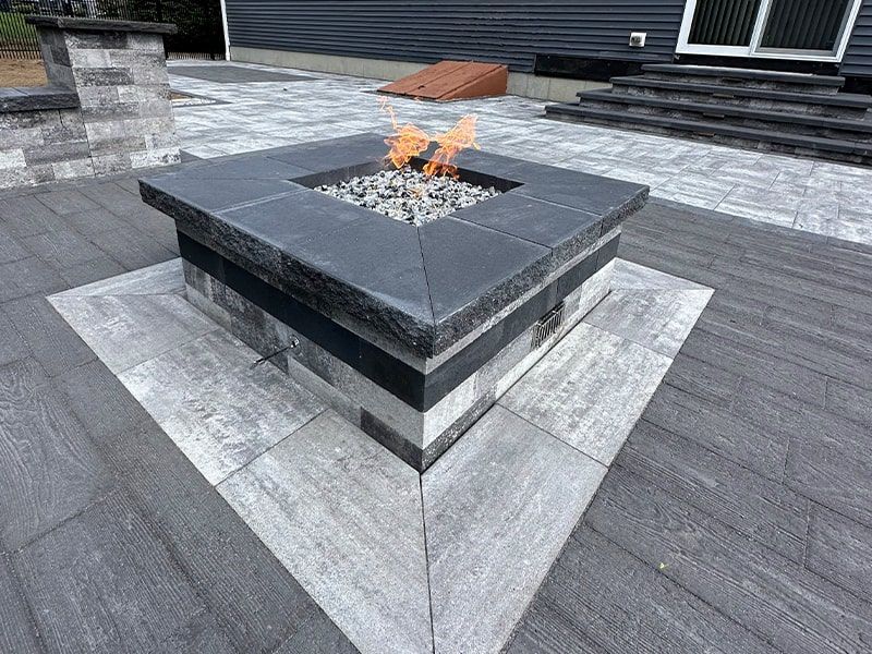 A fire pit is sitting on top of a patio next to a house.