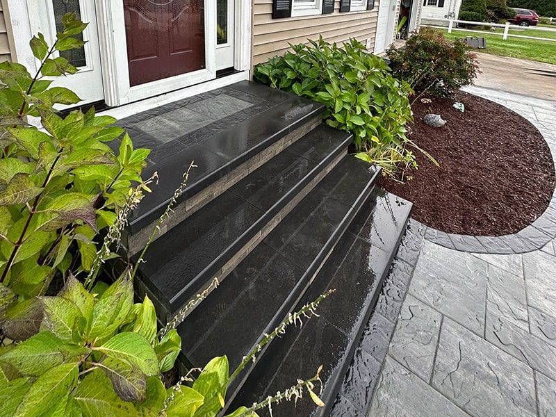 The front steps of a house are made of black granite.