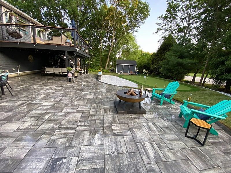 A patio with a fire pit and chairs in front of a house.