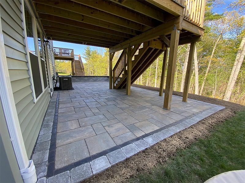 A patio with a deck and stairs underneath it.