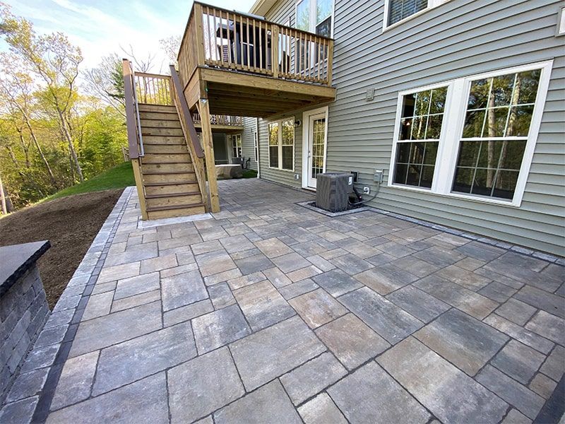 A large patio with a deck and stairs in front of a house.