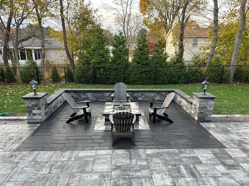 A patio with chairs , a table and a fire pit.