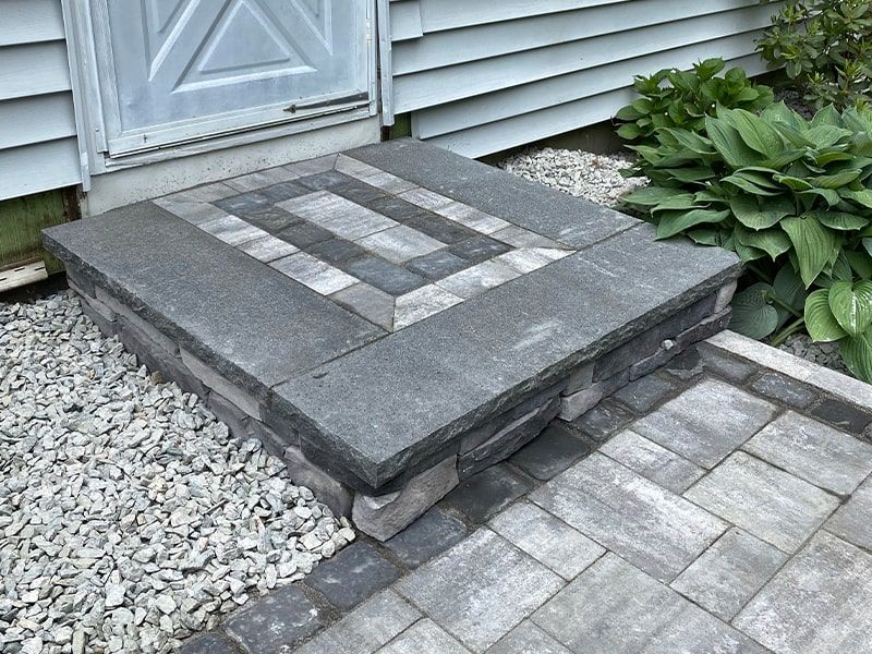 A brick walkway leading to a door with a geometric design on it.