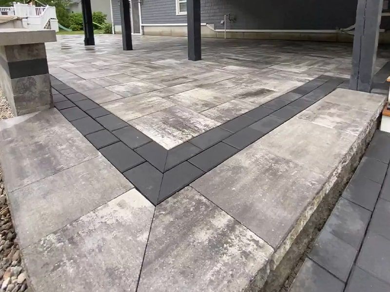 A patio with a black border and steps leading up to it.