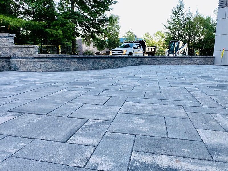 A truck is parked on the side of a brick driveway.
