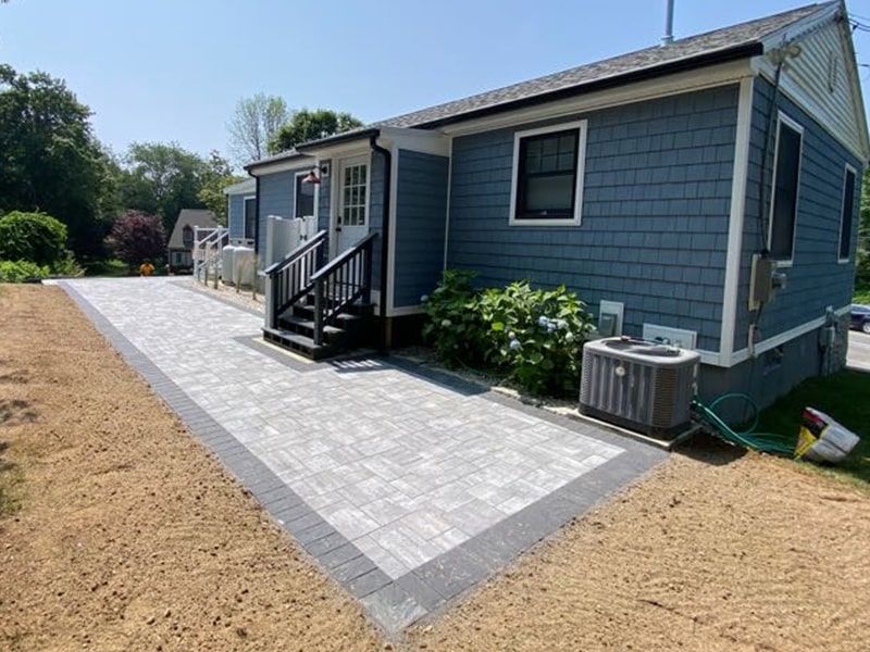 A blue house with a brick walkway leading to it.
