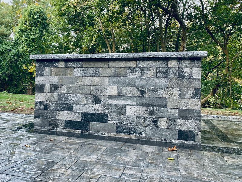 A large brick wall is sitting on top of a brick patio.