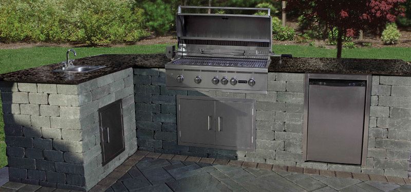 An outdoor kitchen with a grill , sink , and dishwasher.