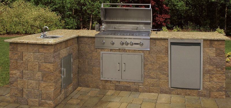An outdoor kitchen with a grill , sink , and refrigerator.