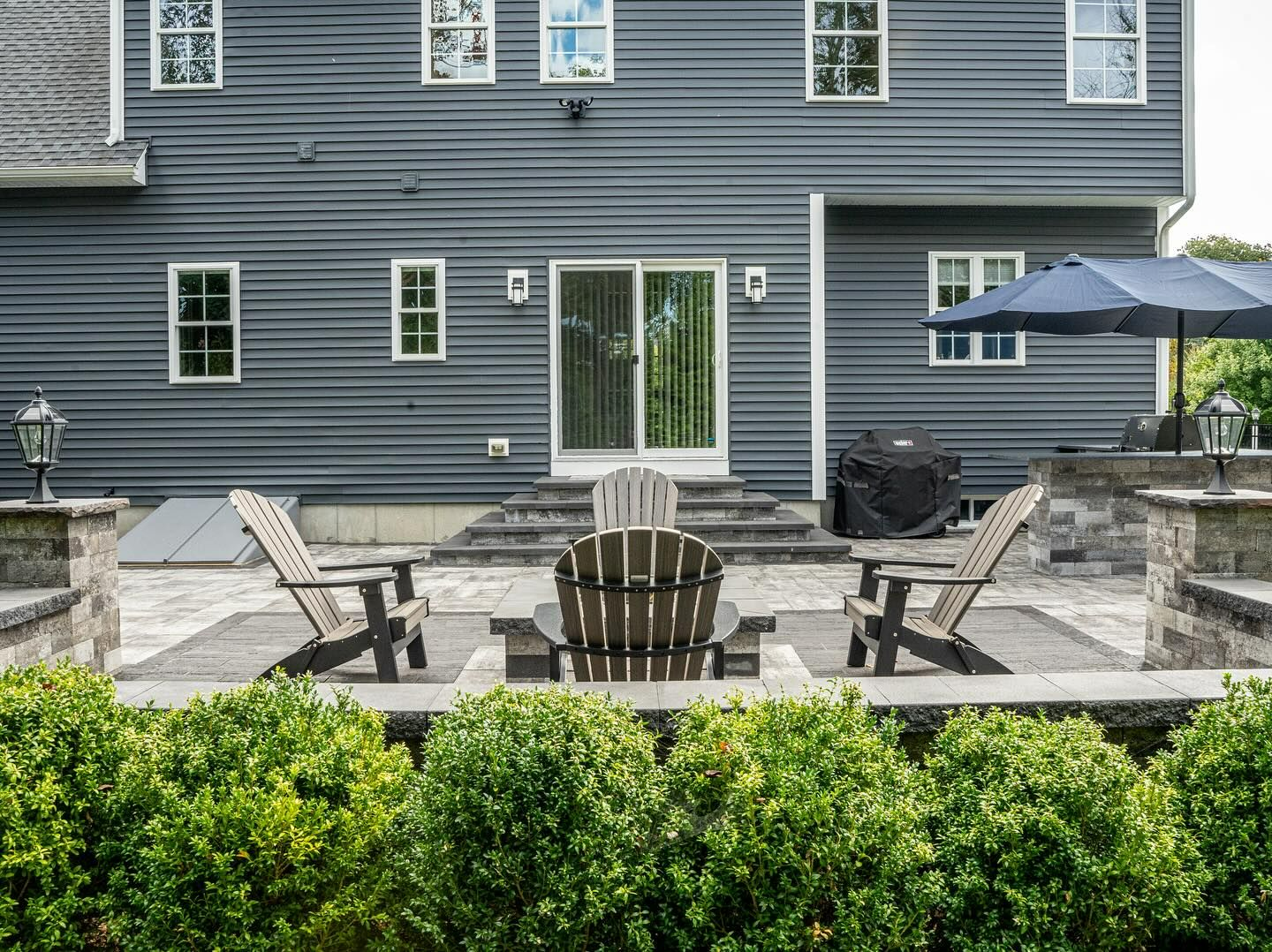 A patio with chairs and umbrellas in front of a house.