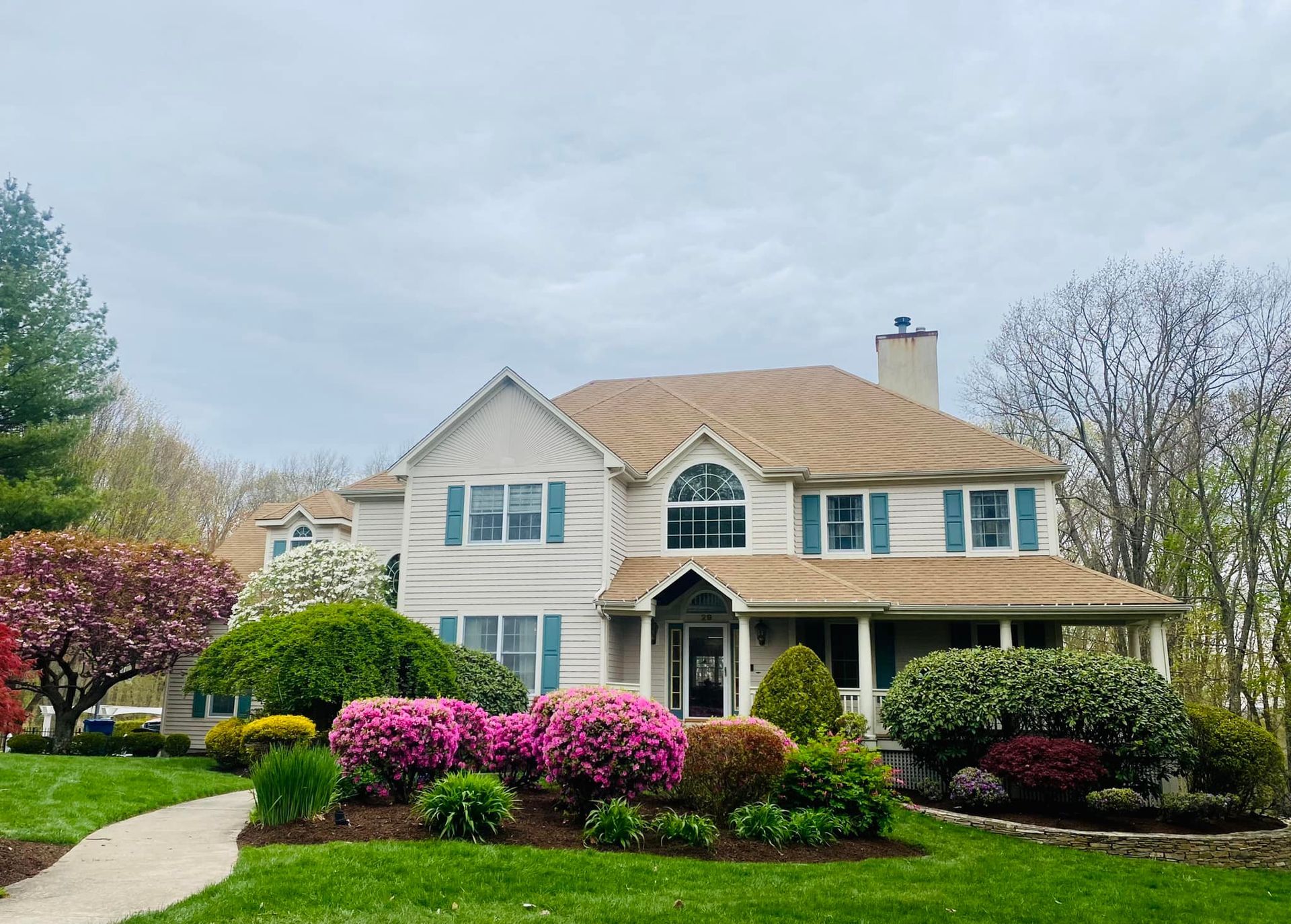 A large white house with a brown roof and blue shutters