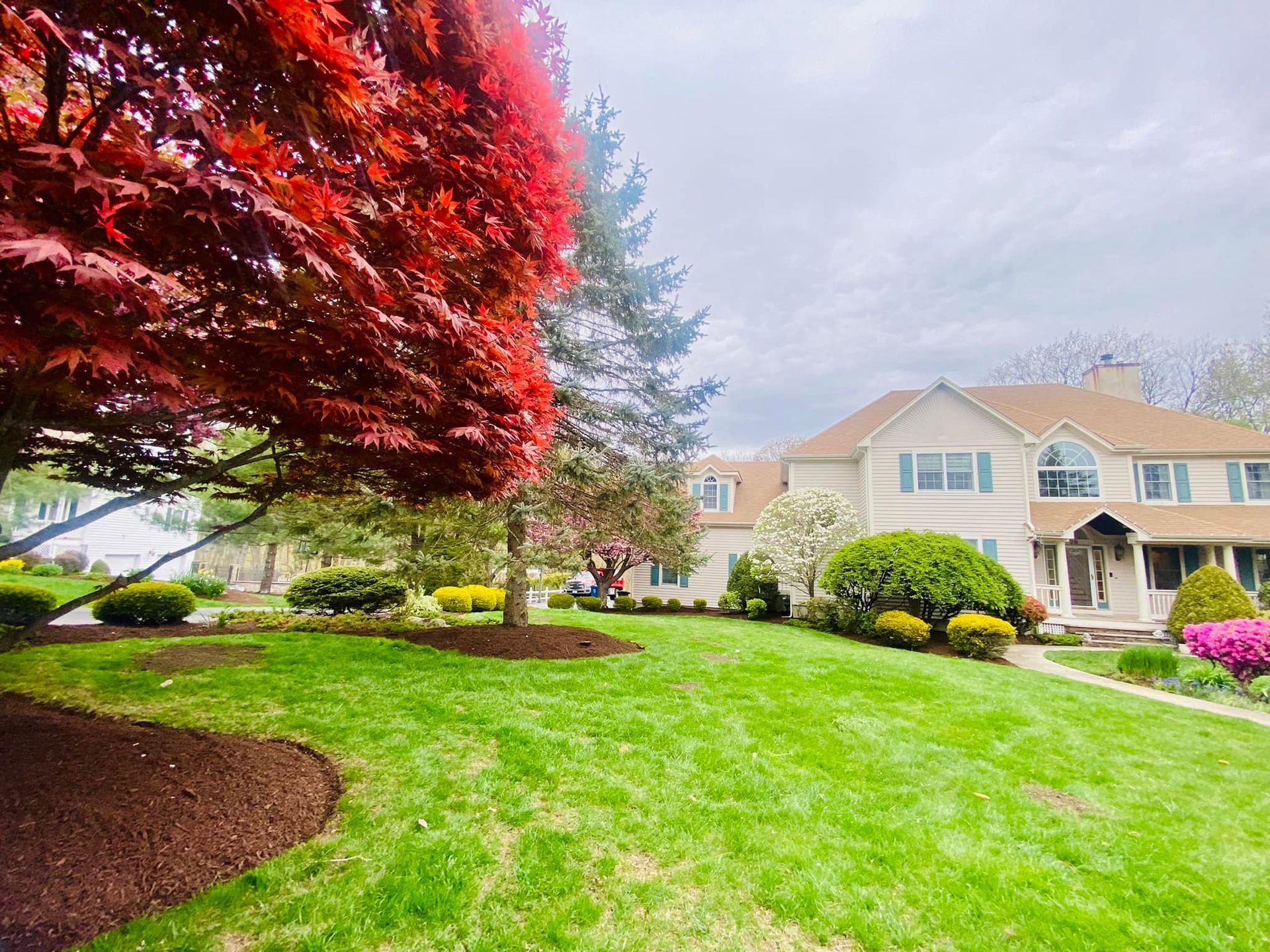 A large house with a lush green lawn and trees in front of it.
