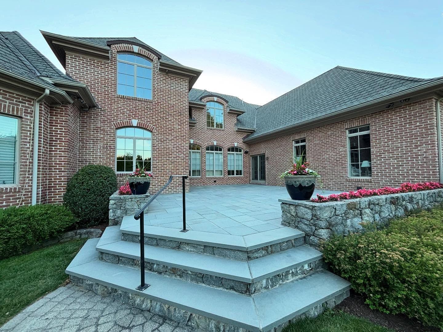 A large brick house with a patio and stairs in front of it.