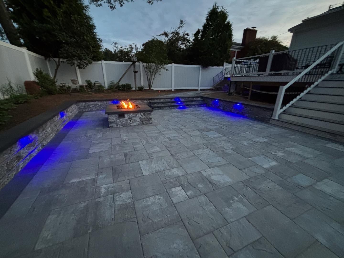 A fire pit is lit up with blue lights in a backyard.