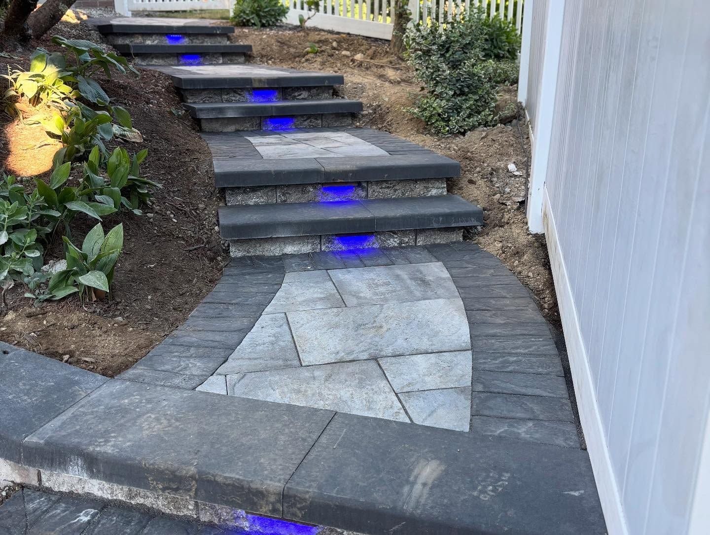 A stone walkway with blue lights on the steps leading up to a house.