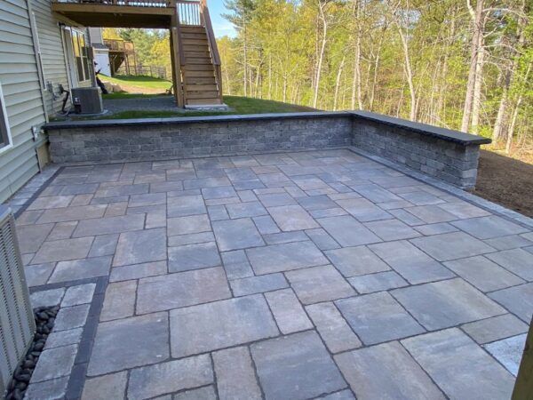 A patio with a wall and stairs in the background.