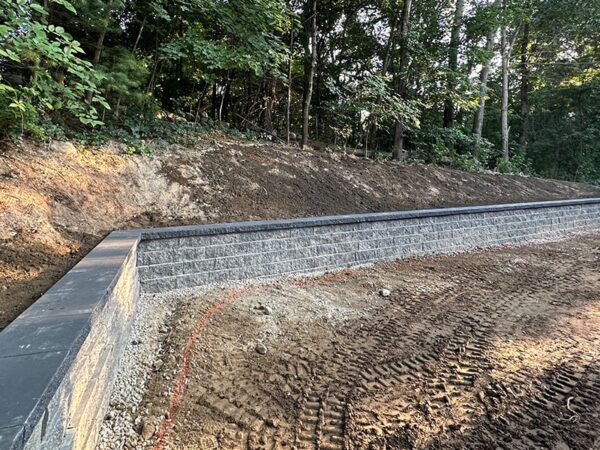 A brick wall is being built in the middle of a dirt field.