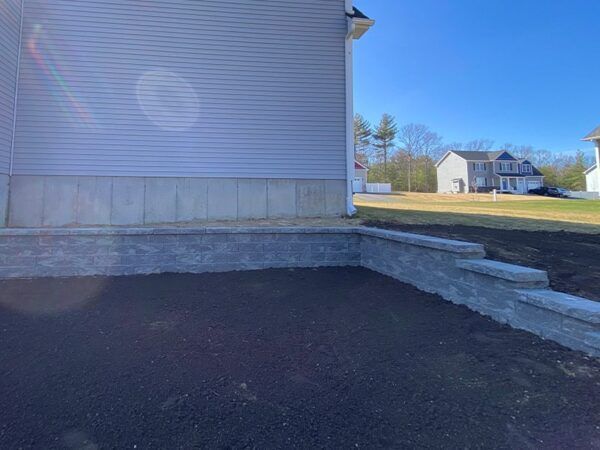 A house with a concrete wall and steps in front of it.